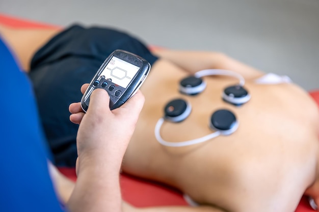 Foto mujer que recibe tratamiento de mioestimulación en clínica de fisioterapia