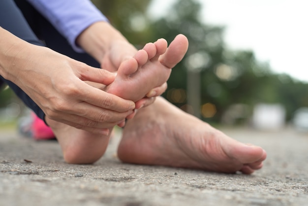 mujer que siente dolor en el pie durante el deporte al aire libre