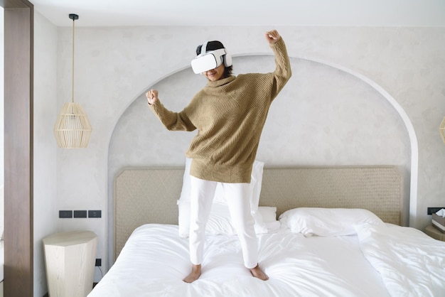 Una mujer que se siente feliz y baila con sus gafas de realidad virtual en la cama