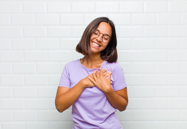 Mujer que se siente romántica, feliz y enamorada, sonriendo alegremente y tomados de la mano cerca del corazón