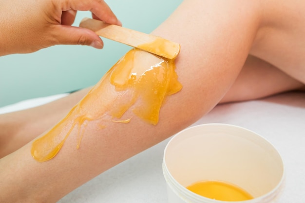 Mujer que se somete a un procedimiento de depilación de piernas con pasta de azúcar en el salón Cuidado de la piel eliminar el vello con pasta de azúcar