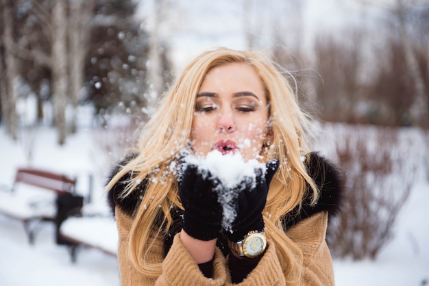 Mujer que sopla nieve en las manos en cámara lenta.