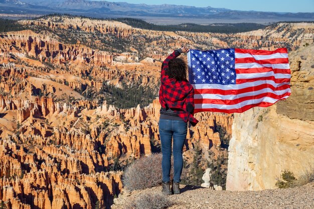 Mujer que sostiene una bandera que disfruta de la vista de un paisaje americano