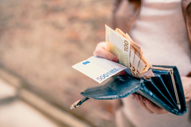 Mujer que sostiene en la billetera de manos con dinero euro. Mujer joven con dinero