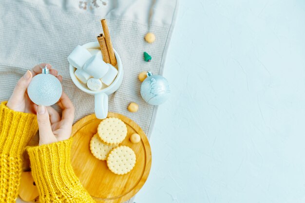 Mujer que sostiene la bola de la Navidad para la decoración con la melcocha del chocolate canela, galletas