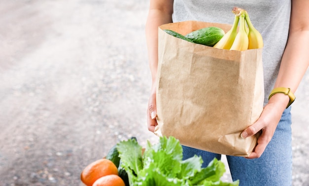 Mujer que sostiene una bolsa de papel de verduras frescas