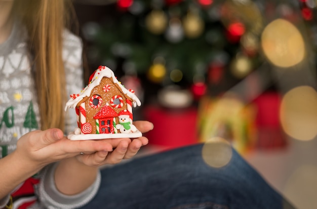 Mujer que sostiene la casa de pan de jengibre de Navidad