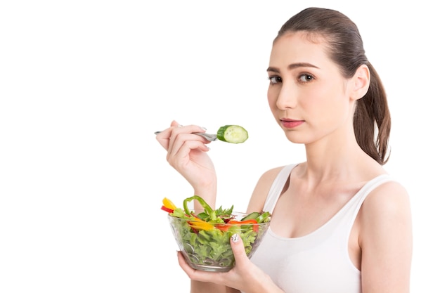 Mujer que sostiene la ensalada de verduras fresca en recipiente de vidrio sobre fondo blanco