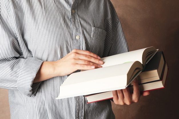 Mujer que sostiene los libros contra el fondo marrón, cierre