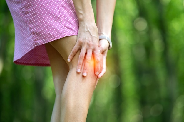 Mujer que sostiene la rodilla con las manos que tienen dolor fuerte.
