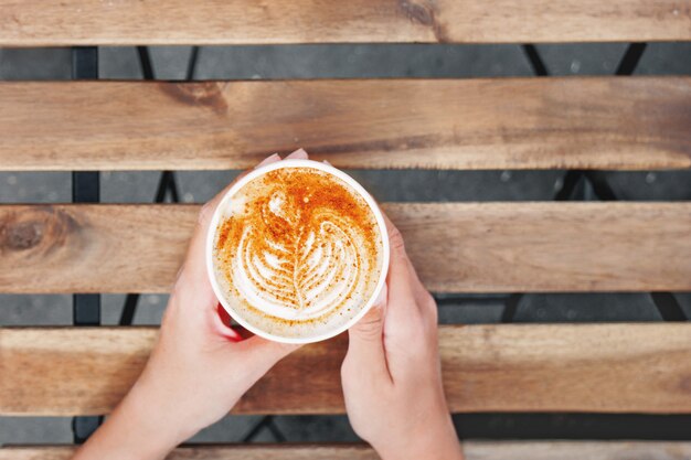 Mujer que sostiene una taza de papel con café.