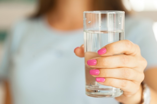 Mujer que sostiene un vaso de agua, primer plano