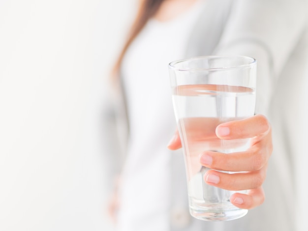 Mujer que sostiene el vidrio de agua potable en su mano. Concepto de cuidado de la salud