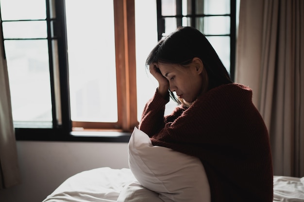 Mujer que sufre de depresión sentada en la cama en el dormitorio