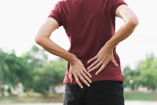 Una mujer que sufre de dolor de espalda, lesión en la columna y problemas musculares en el exterior