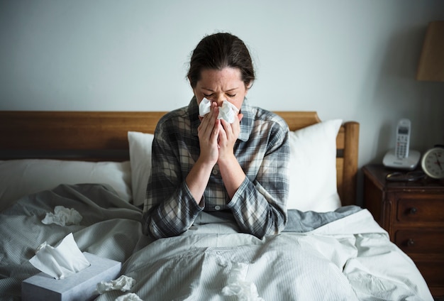 Una mujer que sufre de gripe en la cama.