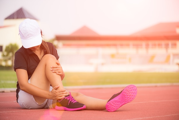 Mujer que sufre de una lesión en el tobillo mientras hace ejercicio, concepto de salud y deporte.