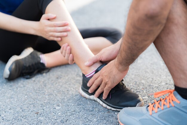 Mujer que sufre de una lesión en el tobillo mientras hace ejercicio, concepto de salud y deporte.