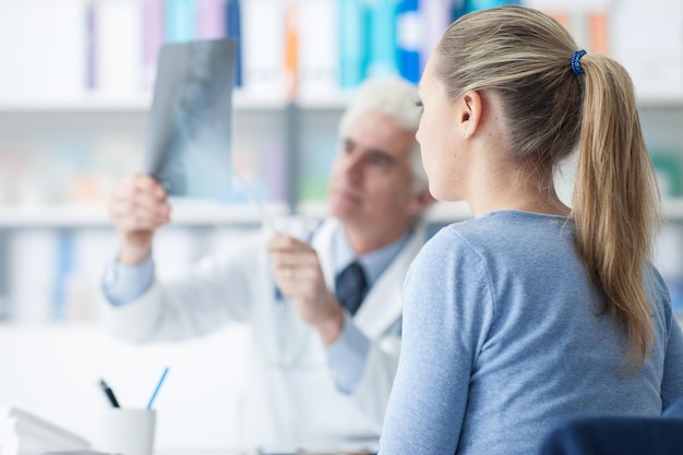 Mujer que tiene una consulta en el consultorio del médico, el médico está examinando un concepto de atención médica por rayos X