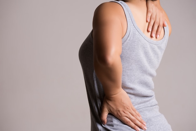 Foto mujer que tiene dolor en la espalda lesionada. la salud y el concepto de dolor de espalda.