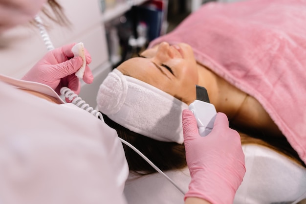 Mujer que tiene un tratamiento facial estimulante de un terapeuta