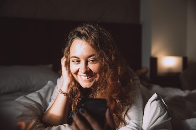 Mujer que tiene una videollamada comunicándose por teléfono celular en casa