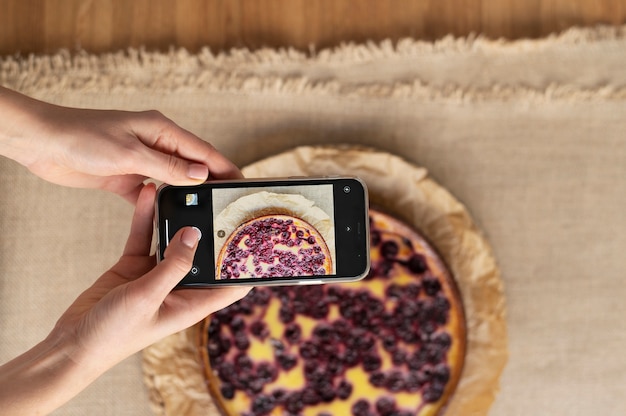 Mujer que toma la foto de la mitad de la tarta de cerezas