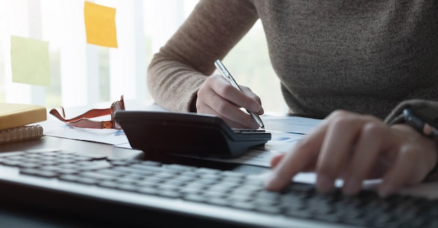 Mujer que trabaja con calculadora para documentos financieros en la oficina. contador masculino haciendo contabilidad y cálculo. Contador haciendo cálculos. Ahorro, finanzas