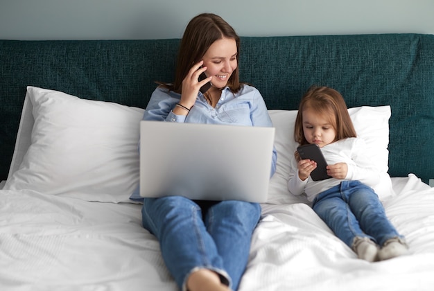 Mujer que trabaja desde casa en la cama con mi hija