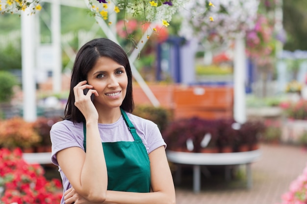 Mujer que trabaja en el centro de jardinería haciendo una llamada