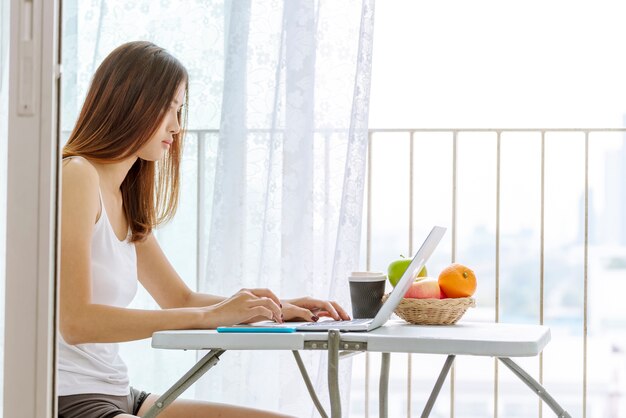 mujer que trabaja en la computadora portátil al aire libre en casa. Hermosas mujeres conectan internet tecnología inalámbrica de internet de trabajo al aire libre