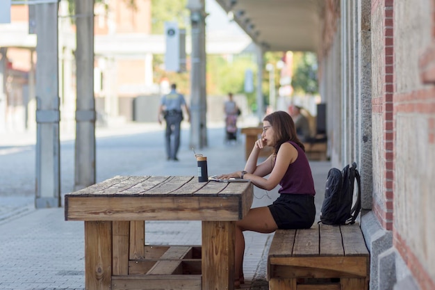 Mujer que trabaja en la computadora portátil al aire libre