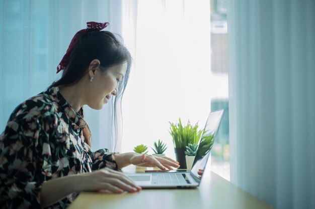 Mujer que trabaja en la computadora portátil en casa mientras habla por teléfono