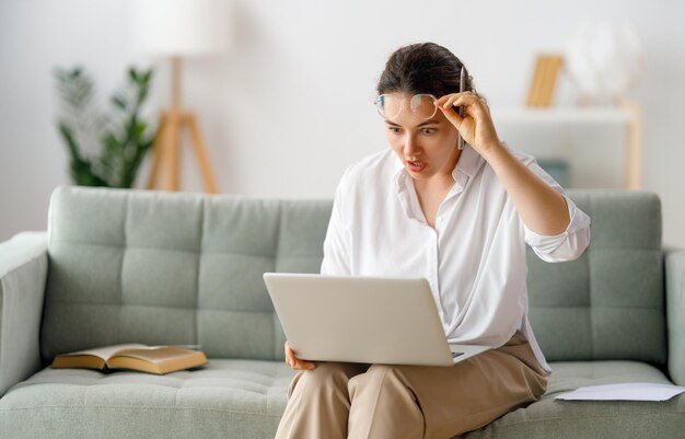 Mujer que trabaja en la computadora portátil en casa