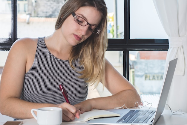 Mujer que trabaja en la computadora portátil en casa.