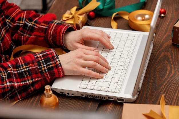 Mujer que trabaja con la computadora portátil y envolver cajas de regalo en una mesa.