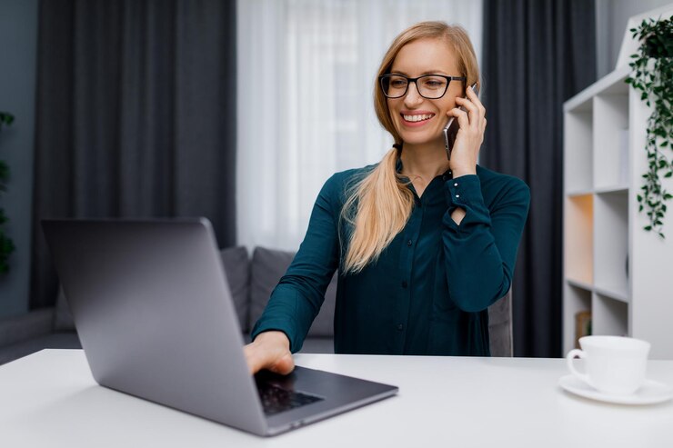 Mujer que trabaja en la computadora portátil y el móvil
