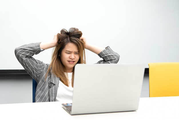 Mujer que trabaja por computadora portátil en la oficina con molesto