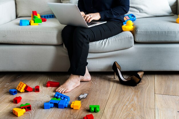 Mujer que trabaja en la computadora portátil en el sofá