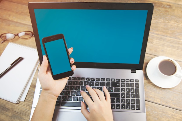 Foto mujer que trabaja en la computadora con smartphone