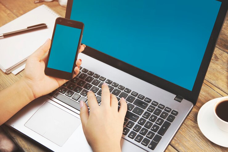Foto mujer que trabaja en la computadora con smartphone
