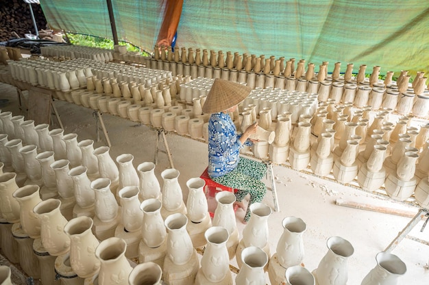 Mujer que trabaja en la fábrica de cerámica Una pila de pequeñas copas de cerámica en bruto en el estante Molde de taza de cerámica Proceso tradicional de fabricación de tazas de cerámica en la fábrica