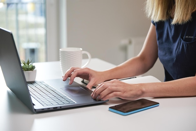 Mujer que trabaja de forma remota desde la oficina en casa usando una computadora portátil