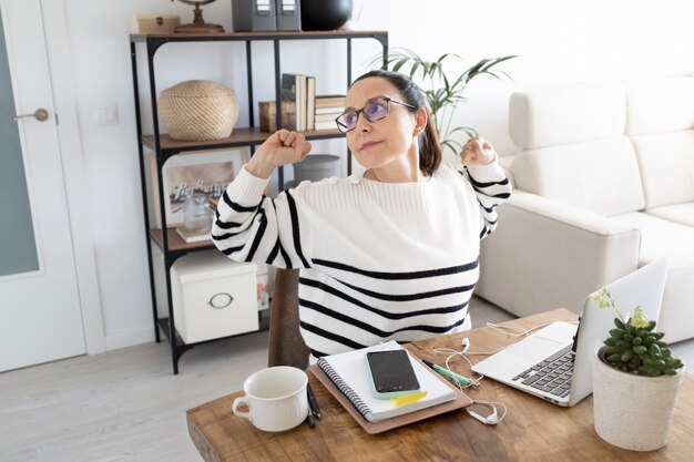 Foto mujer que trabaja en la oficina en casa se extiende para relajar los músculos