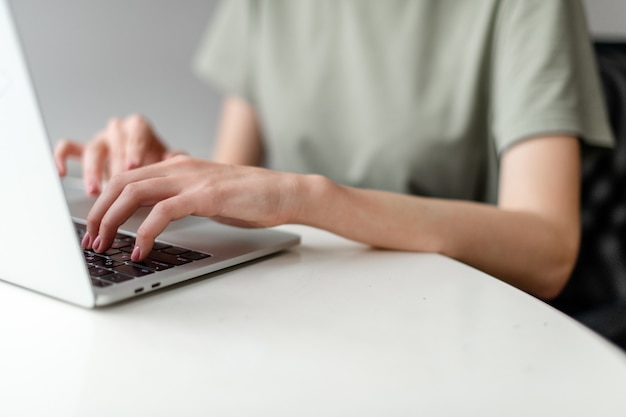 Mujer que trabaja en la oficina en casa con la mano en el teclado cerrar