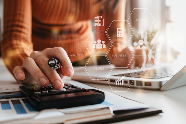 Mujer que trabaja en la oficina de escritorio con una calculadora para calcular los números, concepto de contabilidad financiera.