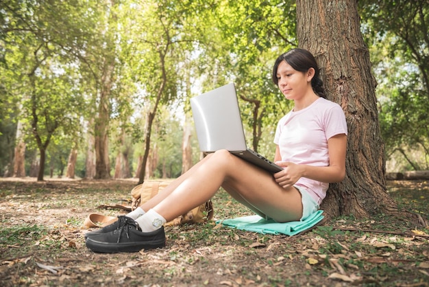 Mujer que trabaja con un portátil en el bosque