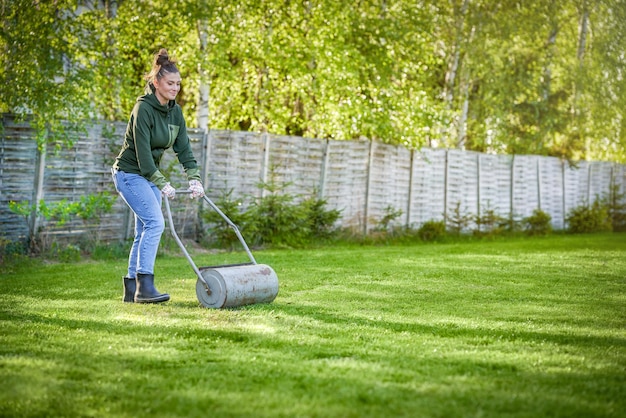 Mujer que trabaja con rodillo de césped en el jardín.