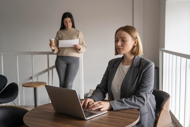 Mujer que trabaja sola mientras se aleja socialmente de otros compañeros de trabajo