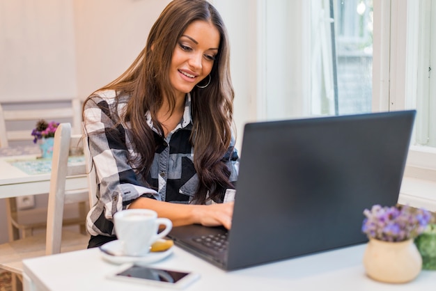 Foto mujer que trabaja en su computadora portátil en un café